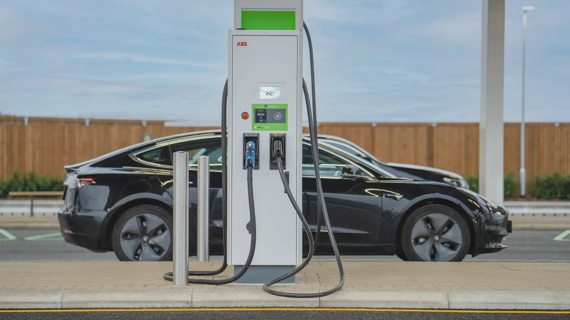 Electric vehicle charging at GRIDSERVE’s Electric Forecourt®, with digital signage integrated near the terminal to enhance the user experience and highlight sustainable mobility.