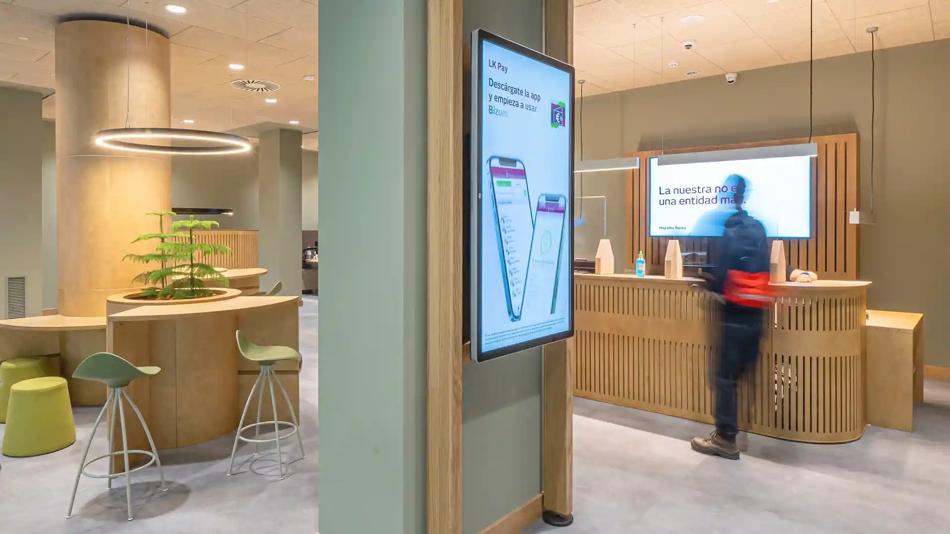 Interior view of a renovated Laboral Kutxa branch showcasing digital signage and updated customer areas.