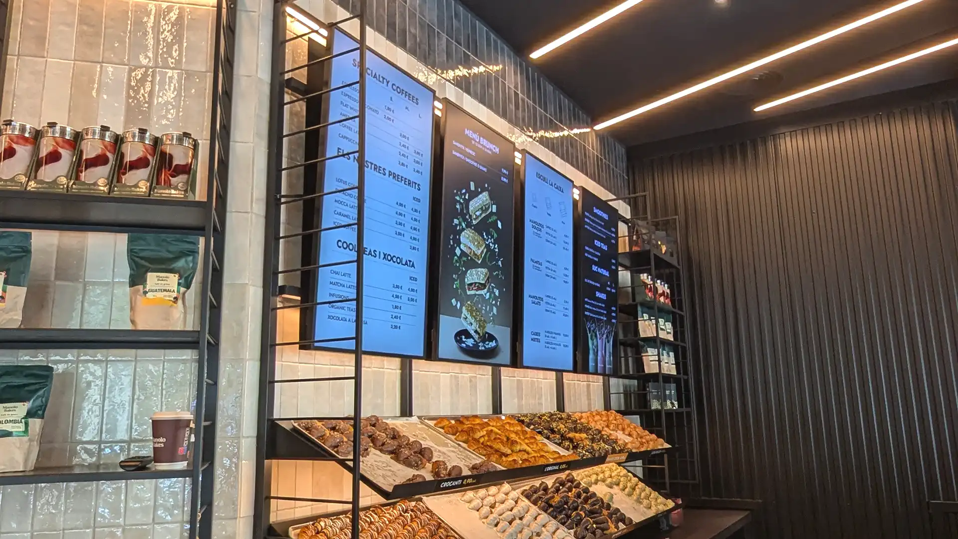 Digital screen at Manolo Bakes showing rotating product offers and dynamic brand visuals.