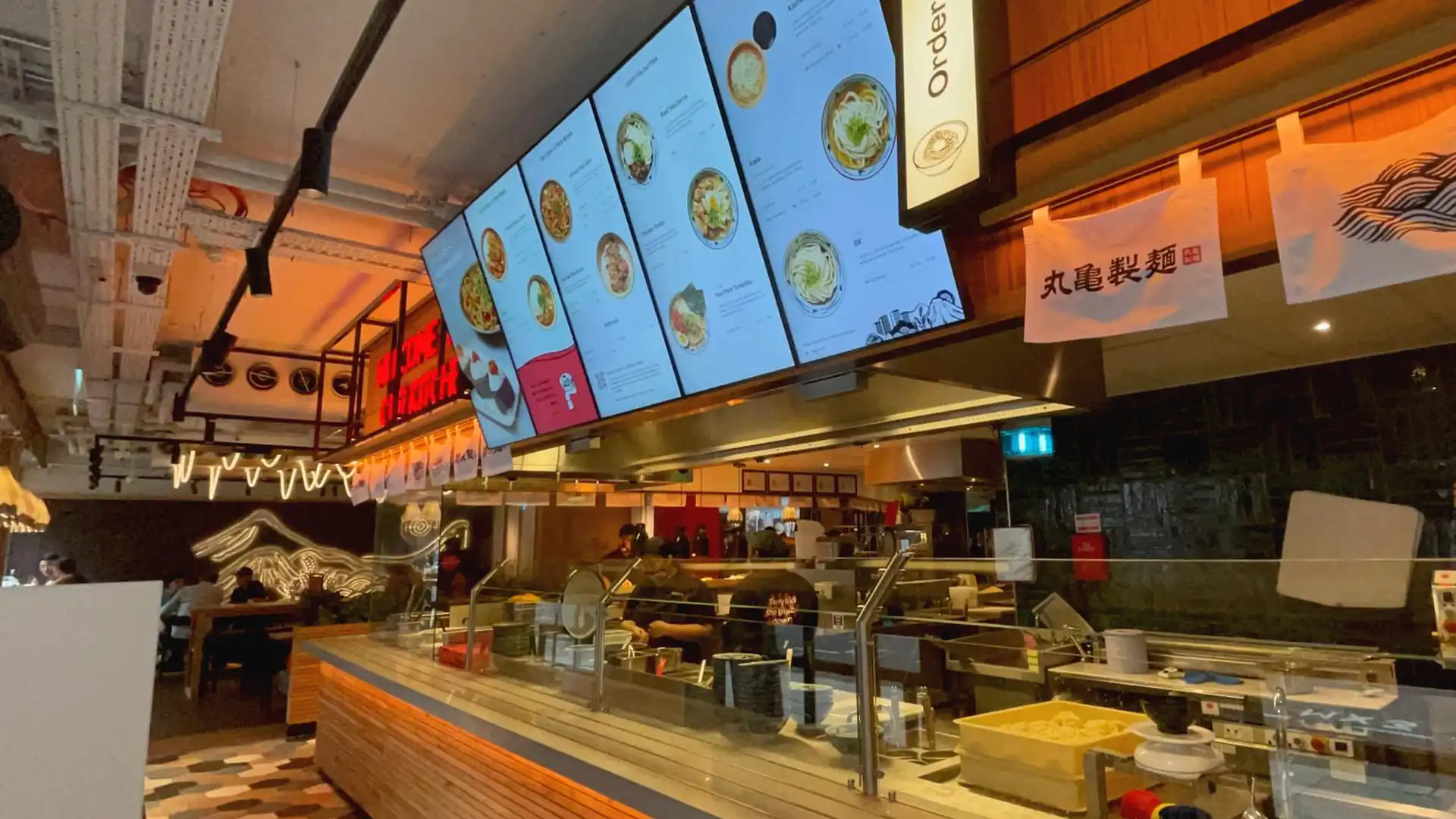 Interior of Marugame Udon London featuring digital screens, interactive menus, and LED installations by TRISON UK.